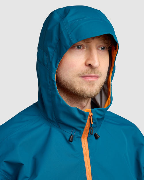 Person wearing a blue raincoat with an orange zipper on a light gray background